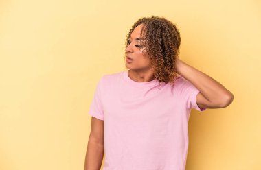 Sarı arka planda izole edilmiş genç Latin transseksüel kadın yorgun ve uykulu ellerini başının üstünde tutuyor..