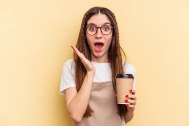 Restoran garsonu elinde kahve tutan kadın sarı arka planda izole edilmiş, şaşırmış ve şok olmuş..