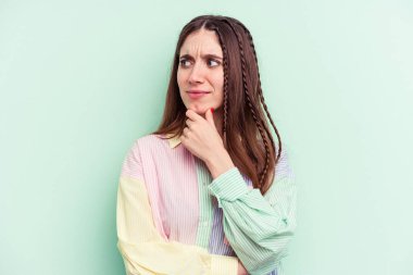 Yeşil arka planda izole edilmiş genç beyaz kadın virüs ya da enfeksiyon yüzünden boğazında ağrı hissediyor..