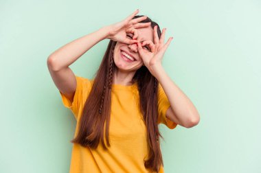 Yeşil arka planda izole edilmiş genç beyaz kadın gözlerinde sorun olmadığını gösteriyor.