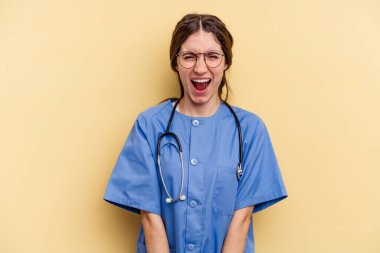 Sarı arka planda izole edilmiş genç beyaz kadın çok sinirli ve agresif bağırıyor..