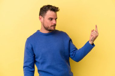 Sarı arka planda izole edilmiş genç beyaz adam sanki seni davet ediyormuş gibi seni işaret ediyor..