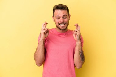 Sarı arka planda izole genç beyaz adam şans dilemek için şans diliyor.