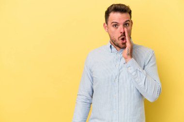 Sarı arka planda izole edilmiş genç beyaz bir adam gizli bir sıcak fren haberi veriyor ve yana bakıyor.