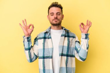 Sarı arka planda izole edilmiş genç beyaz adam sıkı çalışma gününden sonra rahatlıyor. Yoga yapıyor..