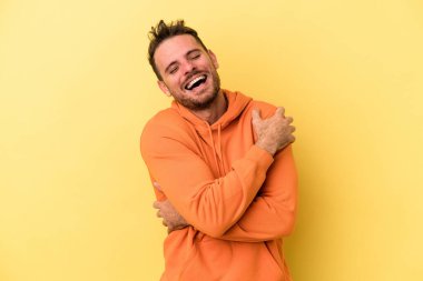 Sarı arka planda izole genç beyaz adam gülüyor ve eğleniyor..
