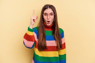 Sarı arka planda izole edilmiş genç beyaz bir kadının bir fikri var, ilham verici bir kavram..