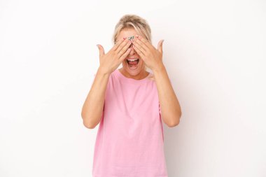 Beyaz arka planda izole edilmiş genç bir Rus kadın elleriyle gözlerini kapatıyor, geniş bir gülümsemeyle bir sürpriz bekliyor..