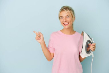 Mavi arka planda demir tutan genç Rus kadın gülümsüyor ve boş alanda bir şey gösteriyor..