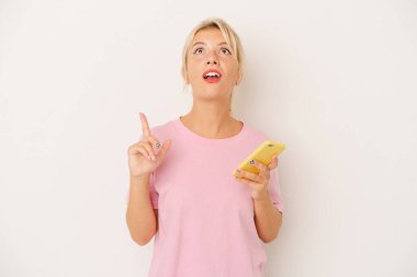 Elinde cep telefonu olan genç bir Rus kadın beyaz arka planda izole edilmiş ve ağzı açık bir şekilde üst tarafı işaret ediyor..