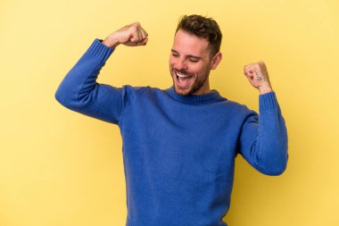 Sarı arka planda izole edilmiş genç beyaz adam tasasız ve heyecanlı bir şekilde tezahürat yapıyor. Zafer konsepti.