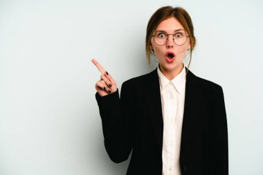 Genç iş kadını. Mavi arka planda izole edilmiş. Yan tarafı işaret ediyor.