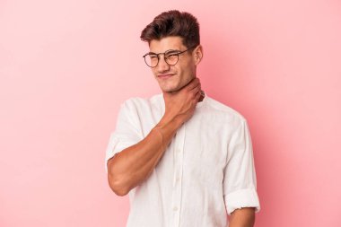 Kafkasyalı genç bir adam pembe arka planda izole edilmiş kafasının arkasına dokunuyor, düşünüyor ve bir seçim yapıyor..