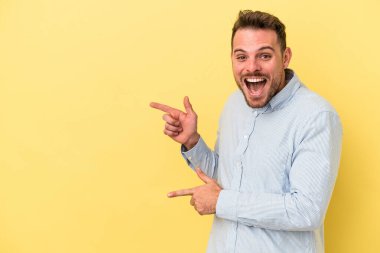 Sarı arka planda izole edilmiş genç beyaz adam işaret fişekleriyle işaret ederek heyecanlanıyor..