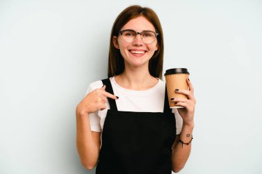 Restoran garsonu elinde mavi arka planda izole edilmiş kahve tutan kadın gömlek fotokopi alanını işaret ediyor, gururlu ve kendinden emin.