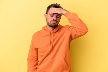 Sarı arka planda izole edilmiş genç beyaz adam tapınaklara dokunuyor ve baş ağrısı çekiyor..