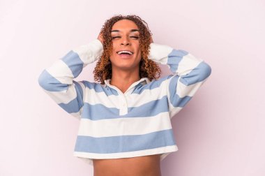 Pembe arka planda izole edilmiş genç Latin transseksüel kadın mutlu bir şekilde ellerini başının üstünde tutuyor. Mutluluk kavramı.