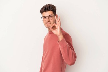 Beyaz arka planda izole edilmiş genç beyaz bir adam bir göz kırptı ve elleriyle iyi bir jest yaptı..