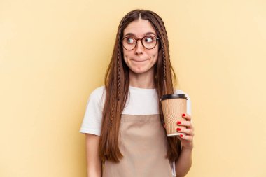 Restoran garsonunun elinde sarı arka planda izole edilmiş kahvesi var. Kafası karışmış, kararsız ve emin değil..