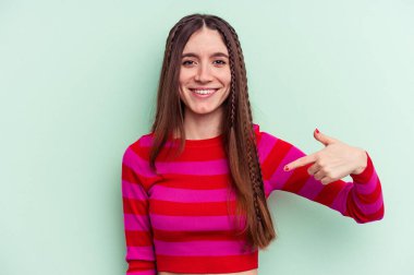 Yeşil arka planda izole edilmiş genç beyaz bir kadın gömleğin fotokopi odasını elle gösteriyor, gururlu ve kendinden emin.