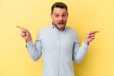 Sarı arka planda izole edilmiş genç beyaz adam farklı kopya alanlarını gösteriyor, birini seçiyor, parmağıyla gösteriyor..