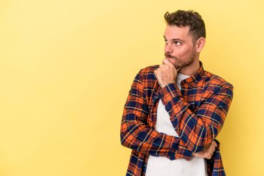 Sarı arka planda izole edilmiş genç beyaz adam rahatlamış bir şeyin fotokopi odasına baktığını düşünüyor..