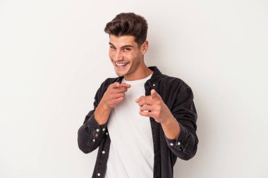 Beyaz arka planda izole edilmiş genç beyaz adam parmaklarıyla ön tarafı işaret ediyor..