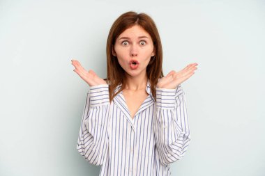 Mavi arka planda izole edilmiş genç bir İngiliz kadın şaşırdı ve şok oldu..