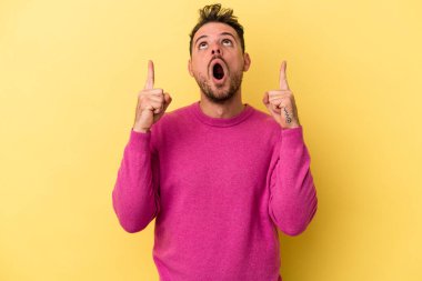 Sarı arka planda izole edilmiş beyaz bir adam ağzı açık bir şekilde üst tarafı işaret ediyor..