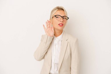 Genç iş kadını, beyaz arka planda izole edilmiş bir şekilde bir dedikoduyu dinlemeye çalışıyor..