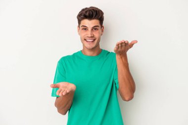 Beyaz arka planda izole genç beyaz adam kollarıyla ölçek yapar, mutlu ve kendinden emin hisseder..