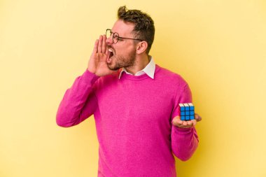Rubiks küpünü tutan genç beyaz adam arka planda izole edilmiş bağırıyor ve avuç içini açık tutuyordu..