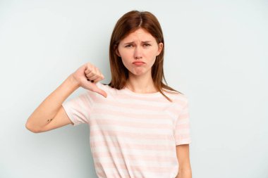 Mavi arka planda izole edilmiş genç İngiliz kadın baş parmağını aşağı gösteriyor, hayal kırıklığı konsepti..