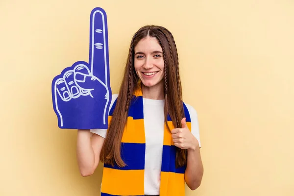 Young sports fan woman isolated on yellow background smiling and raising thumb up