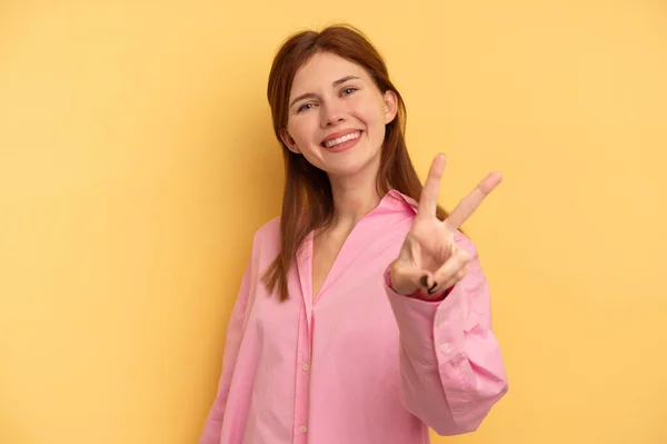 Junge Engländerin Auf Gelbem Hintergrund Zeigt Siegeszeichen Und Lächelt Breit — Stockfoto