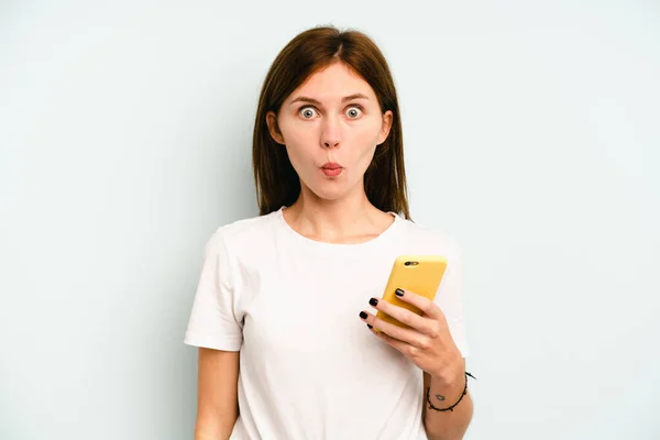 Молодая Английская Женщина Держит Мобильный Телефон Изолирован Синем Фоне Пожимает — стоковое фото
