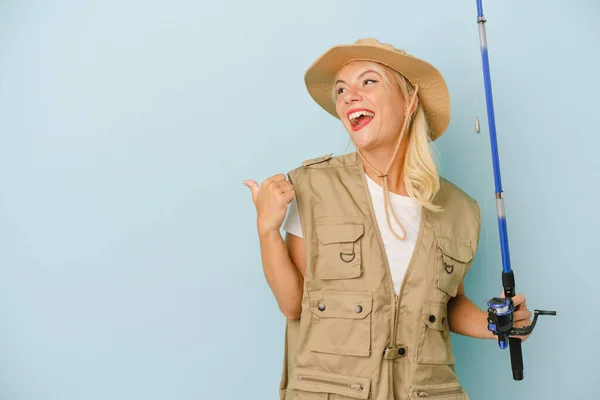 Young Russian Fisherwoman Isolated Blue Background Points Thumb Finger Away — Stock Photo, Image