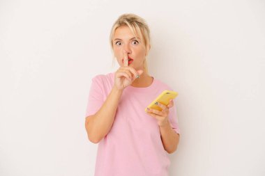 Beyaz arka planda cep telefonu tutan genç Rus kadın ya sır saklıyor ya da sessizlik istiyor..