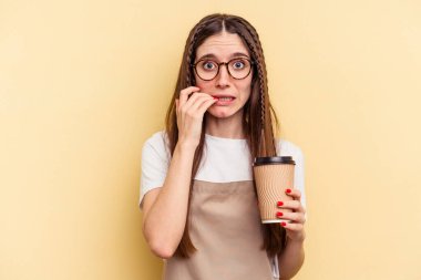 Restoran garsonu elinde kahve tutan kadın sarı arka planda izole edilmiş tırnak yiyor, gergin ve endişeli..