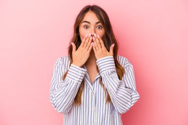 Pembe arka planda izole edilmiş beyaz bir kadın elleriyle ağzını kapatırken şok oldu..