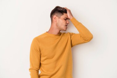 Beyaz arka planda izole edilmiş genç beyaz bir adam bir şeyi unutuyor. Alnına avuç içi ve gözlerini kapayarak vuruyor..