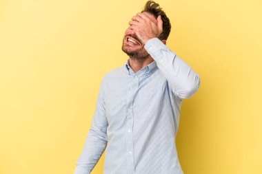 Sarı arka planda izole edilmiş genç beyaz adam elleriyle gözlerini kapatıyor, geniş bir gülümsemeyle bir sürpriz bekliyor..