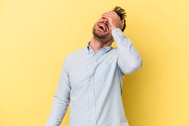 Sarı arka planda izole edilmiş genç beyaz adam ellerini başının üstünde tutarak neşe içinde gülüyor. Mutluluk kavramı.