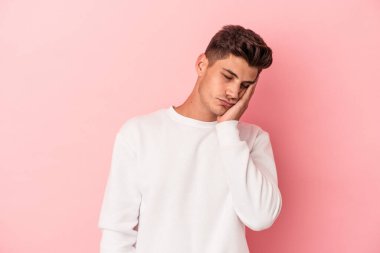 Pembe arka planda izole edilmiş genç beyaz adam sıkılmış, yorgun ve dinlenmeye ihtiyacı var..