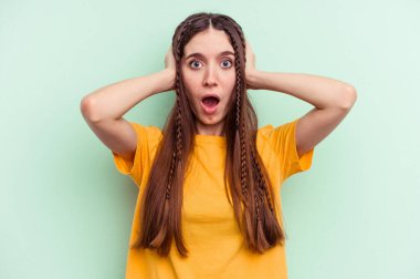 Kafkasyalı genç bir kadın yeşil arka planda izole edilmiş kulakları kulaklarıyla kapatıyor çok fazla ses duymamaya çalışıyor..