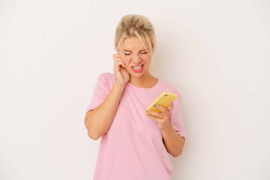 Cep telefonu tutan genç Rus kadın beyaz arka planda izole edilmiş kulakları elleriyle kapatıyor..