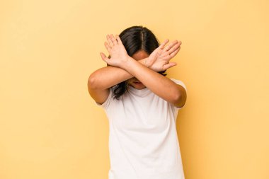 Sarı arka planda izole edilmiş genç Latin kadın iki kolu çapraz tutuyor, inkar kavramı.