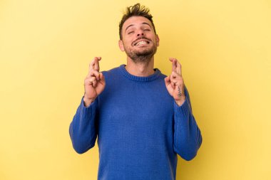 Sarı arka planda izole genç beyaz adam şans dilemek için şans diliyor.