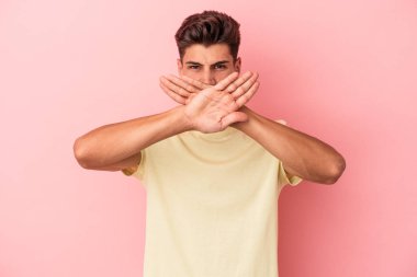 Pembe arka planda izole edilmiş genç beyaz adam inkar jesti yapıyor.
