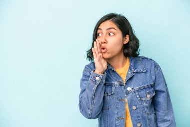 Mavi arka planda izole edilmiş genç Latin kadın gördüğü bir şey yüzünden şoka uğruyor..